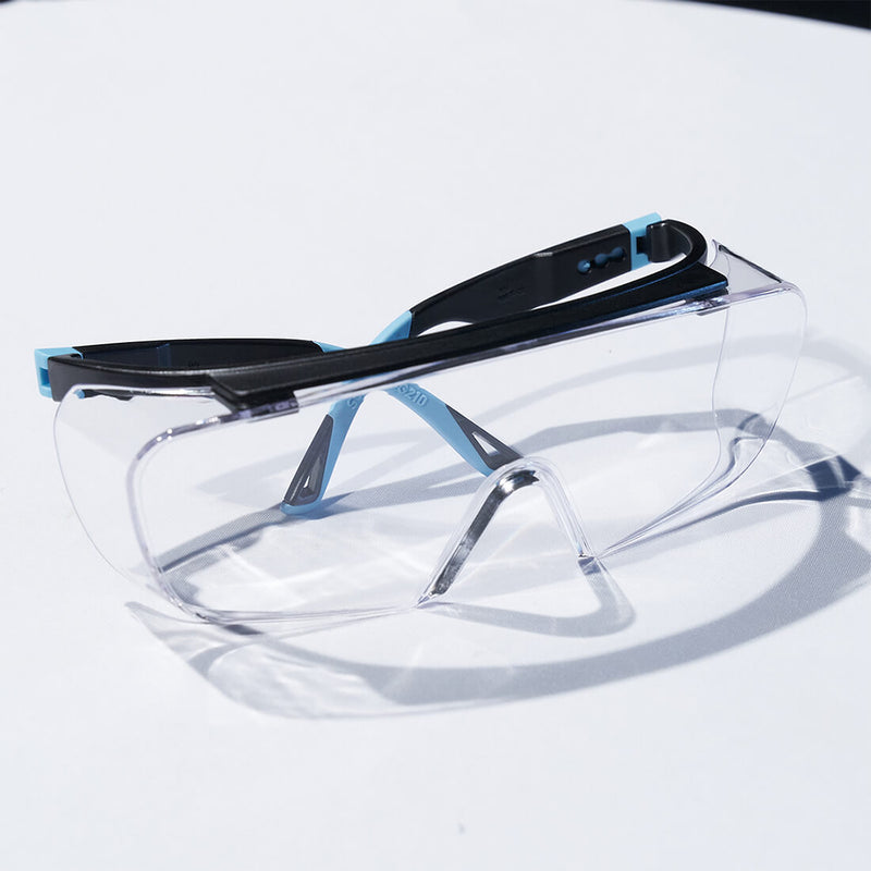 Load image into Gallery viewer, Safety Over Glasses SG210 OTG in Blue with its arms folded emphasizing its wraparound lenses that help protect the eyes from dirt.
