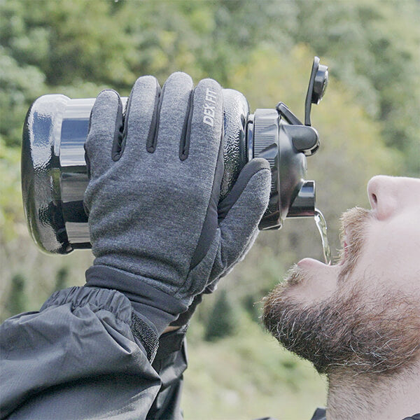 A man using the Black Warm Outdoor Gloves LG201 by DEX FIT MUVEEN while drinking and resting from mountain hiking.