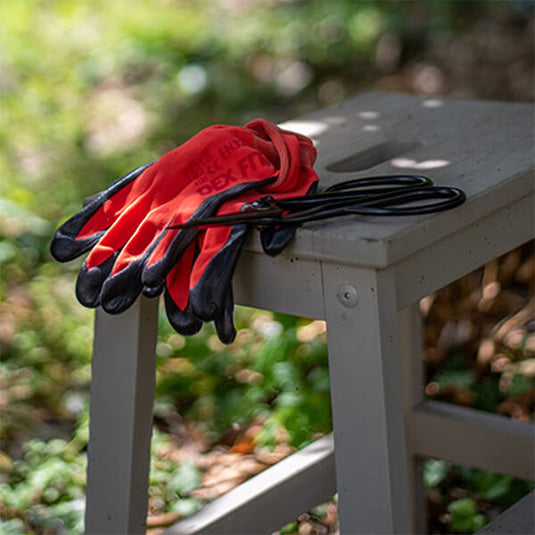 The Multi-Purpose Nylon Work Gloves FN320 in Red beside a sharp scissor, ready to protect for any job.
