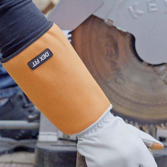 The Leather Gardening Gloves FG310 being used while cutting wood, emphasizing the gauntlet design which protects the hands and forearms from potential accidents.