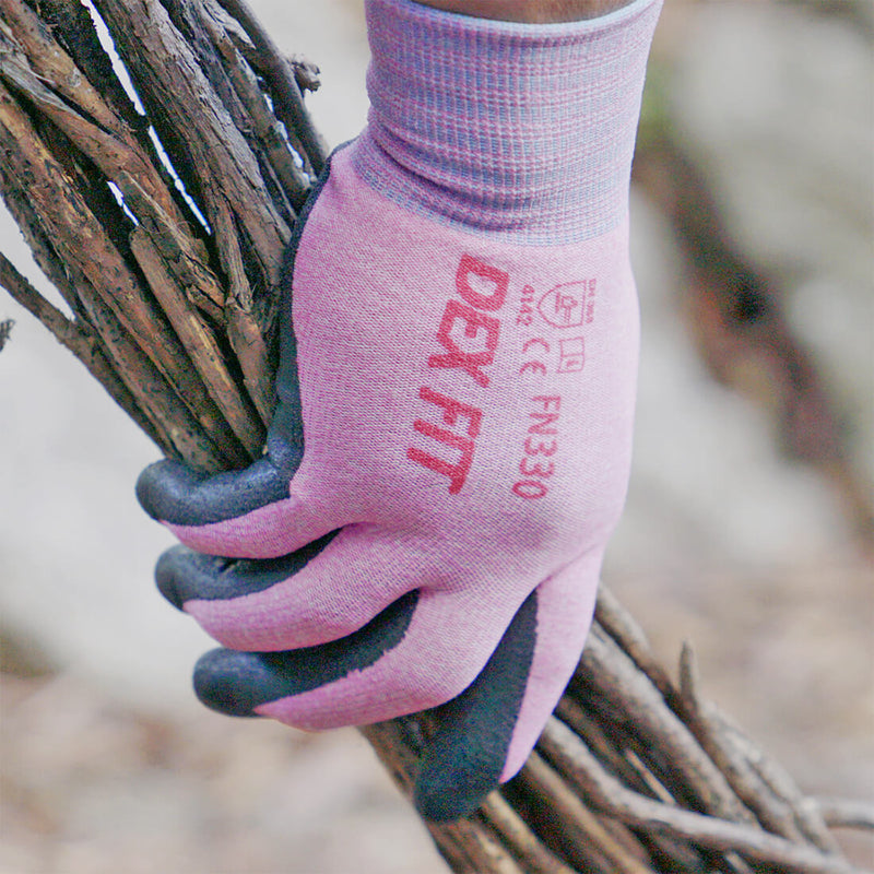 Load image into Gallery viewer, The Nitrile-Coated Work Gloves FN330 in Pink worn while holding a bunch of branches and still keeping the hand protected.
